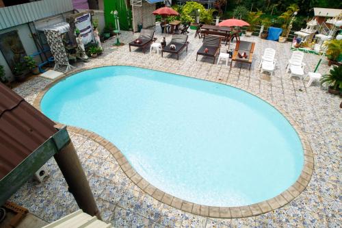 a large blue swimming pool with chairs and tables at Noble Night Guesthouse in Kanchanaburi