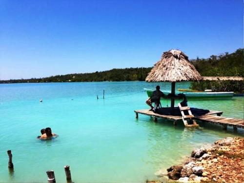 a group of people sitting on a dock in the water at Ecocamping Yaxche in Bacalar