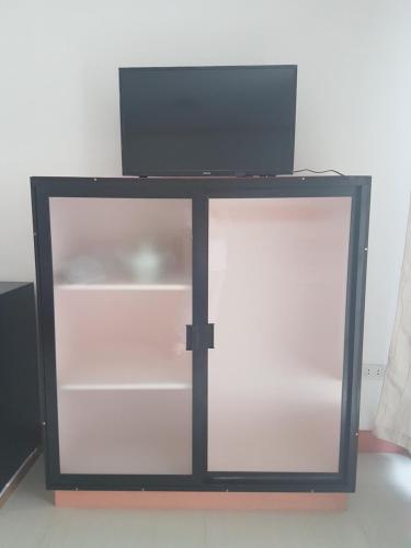 a glass cabinet with a tv on top of it at Catalina`s Inn family room in Panglao
