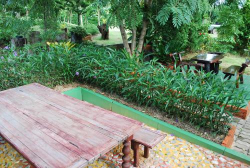 a wooden bench sitting in a garden with plants at Prue Sa Raj in Phetchabun