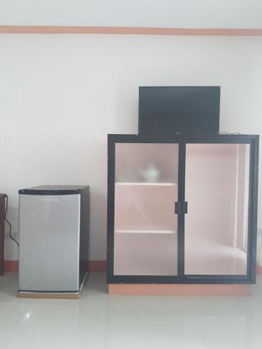a glass cabinet with a tv on top of it at Catalina`s Inn family room in Panglao