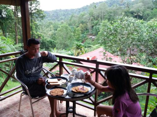 a man and a girl sitting at a table with food at Highland Resort & Nature Tours in Tomohon