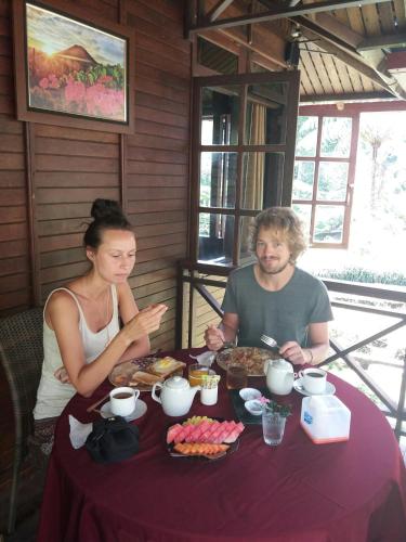 a man and a woman sitting at a table with food at Highland Resort & Nature Tours in Tomohon