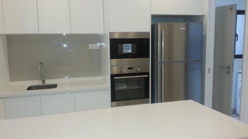 a kitchen with white cabinets and a stainless steel refrigerator at The Horizon Residences in Kuala Lumpur