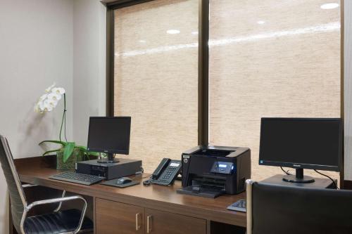 a desk with two monitors and a computer on it at Matiz Multi Suites in Duque de Caxias