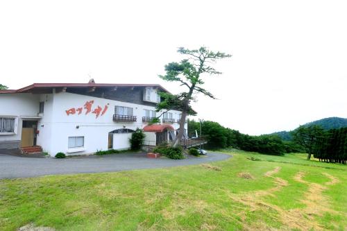 a white building with a grassy yard in front of it at Lodge Sano in Daisen