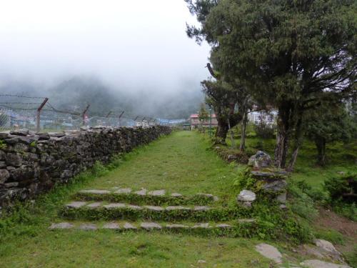 a stone wall and some stairs in a field at Lukla Airport Resort Lukla in Lukla