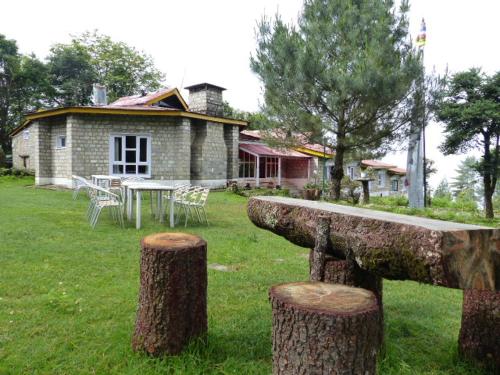 a stone house with a table and chairs and trees at Lukla Airport Resort Lukla in Lukla