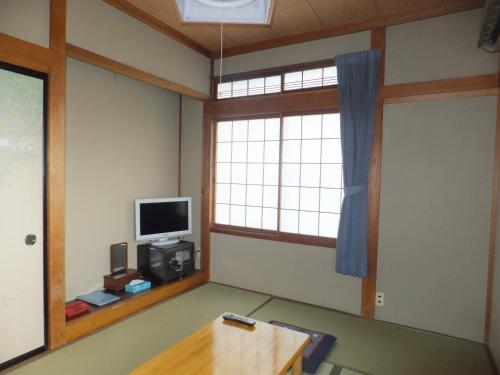 a room with a table and a television and a window at Minshuku Iwatakan in Takayama