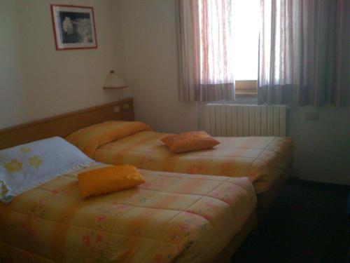 two twin beds in a room with a window at Hotel Genziana in Passo Stelvio