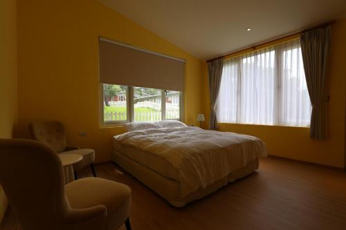 a bedroom with a bed and a chair and a window at American Village Resort in Taipei