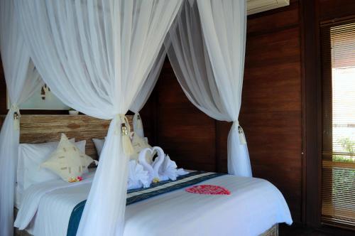 a bedroom with two beds with white curtains at Ocean Terrace Suite And Spa Luxury in Nusa Penida
