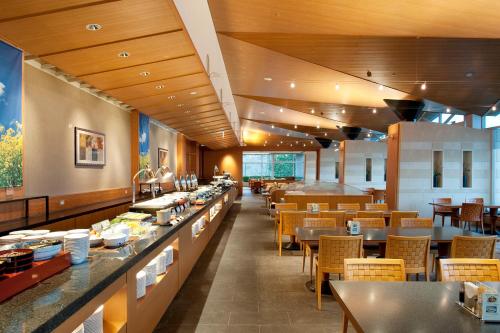 a restaurant with a long counter and tables and chairs at Miyako Resort Okushima Aqua Forest in Shima