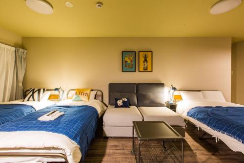 een kamer met drie bedden en een tafel erin bij Sky Living Namba in Osaka