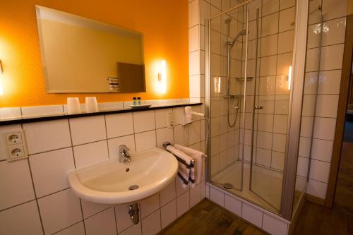 a bathroom with a sink and a shower at Hotel Garni Zur Alten Post in Lembruch