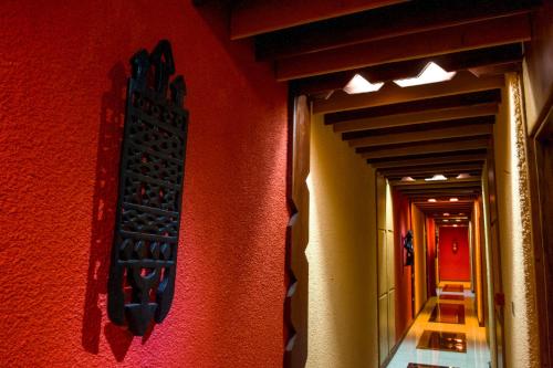 a hallway with a red wall with a sign on it at Hotel Jardin Savana Dakar in Dakar