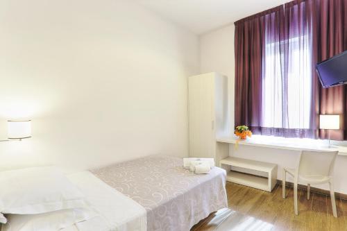 a bedroom with a bed and a desk and a window at Hotel La Pineta in Follonica