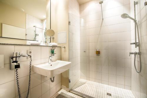a bathroom with a shower, sink, and toilet at Mondrian Suites Berlin am Checkpoint Charlie in Berlin