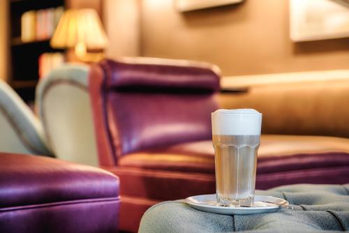 a glass of beer sitting on a table with a chair at Mondrian Suites Berlin am Checkpoint Charlie in Berlin