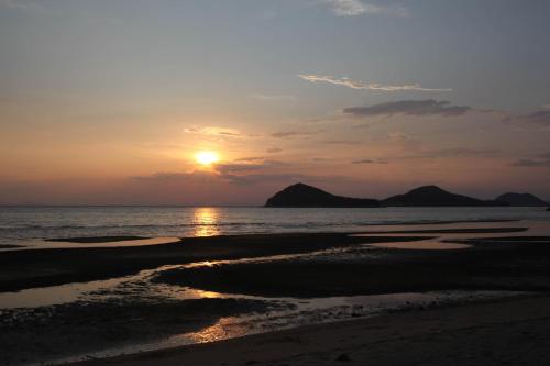 a sunset on a beach with the ocean at WeBase TAKAMATSU in Takamatsu