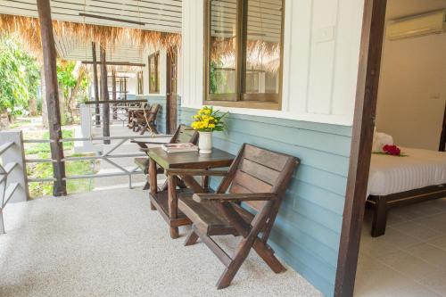 a porch with chairs and a table with flowers on it at Adarin Beach Resort in Mae Nam
