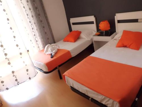 a bedroom with two beds with a stuffed animal on a chair at Hostal Lima in Valladolid
