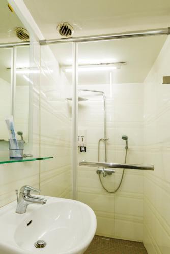a white bathroom with a sink and a shower at Shihlin Metro Home in Taipei