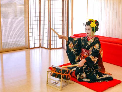 a woman in a kimono sitting on a red rug at Awara Onsen Minoya Taiheikaku in Awara