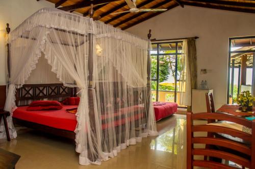 a bedroom with a canopy bed with white mosquito nets at Hotel Panorama in Unawatuna