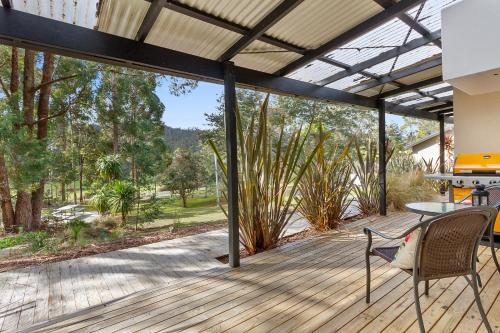 an open patio with a table and chairs on a deck at Oyster Cove Chalet in Kettering