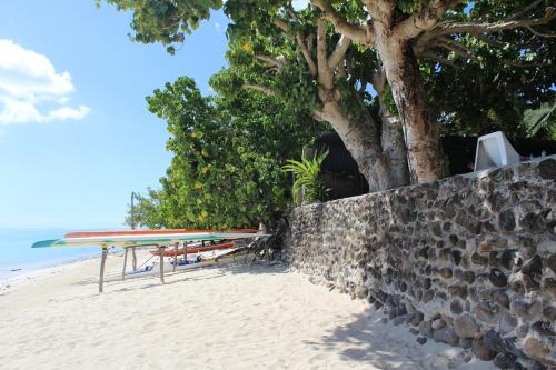 a table and surfboards on a beach next to a wall at Fare Edith Moorea in Haapiti