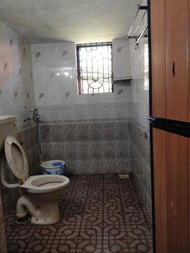 a bathroom with a toilet and a tiled floor at Koito-House calangute guest house in Calangute