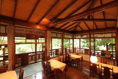a dining room with tables and chairs and windows at 小さなホテルセラヴィ in Nagatoro