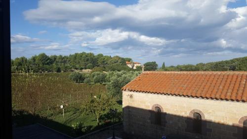 a building with a red tile roof and a field at SERRA E MESU Affittacamere in Magomadas