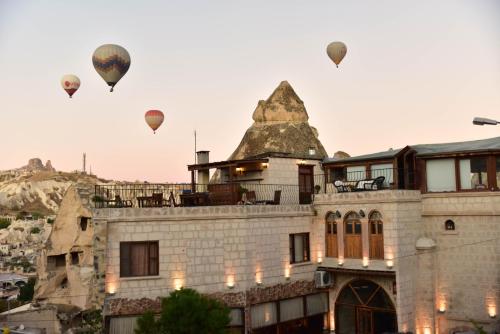 een groep heteluchtballonnen die over een gebouw vliegen bij Ascension Cave Suites - Special Class in Goreme