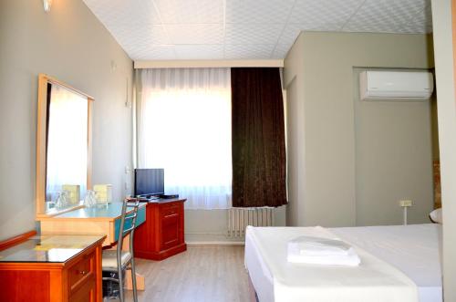 Habitación de hotel con cama, escritorio y ventana en Elit Hotel Saray, en Saray