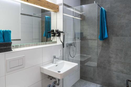 uma casa de banho com um lavatório e um chuveiro com um espelho. em Pension und Appartements Wild em Otterfing