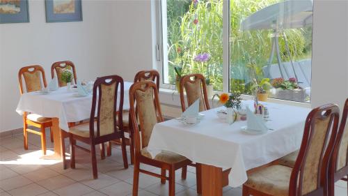 un comedor con mesas y sillas blancas y una ventana en Pension Am Bodden, en Ribnitz-Damgarten