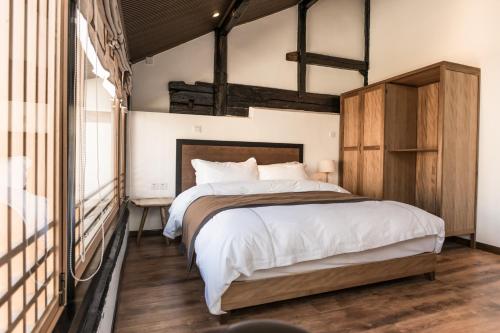 a bedroom with a large bed with a wooden headboard at Dali Shaxi Qing Jing Courtyard in Jianchuan