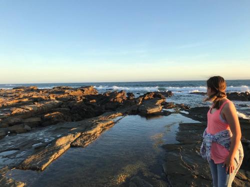 a woman standing on the rocks at the beach at Beautiful, Cosy and Quiet in Cape Paterson