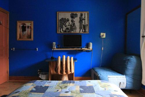 Ein blaues Zimmer mit einem Bett und einem Schreibtisch mit einem Computer. in der Unterkunft Gite L'Imprévu in Montreal