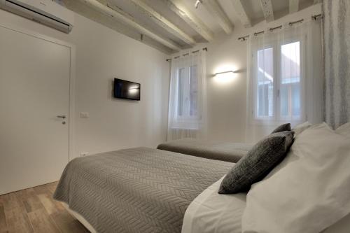 Un dormitorio blanco con dos camas y una ventana. en Castello - Laguna Luxury Residence by Wonderful Italy, en Venecia