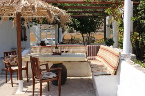 a patio with a table and a bench and an umbrella at Traditional House by The Beach in Agia Theodoti