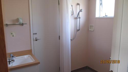 biała łazienka z umywalką i prysznicem w obiekcie Ahuriri Motels w mieście Omarama