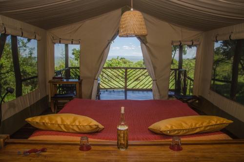 ein Schlafzimmer mit einem Bett in einem Zelt mit Fenstern in der Unterkunft Mara Siria Tented Camp & Cottages in Aitong