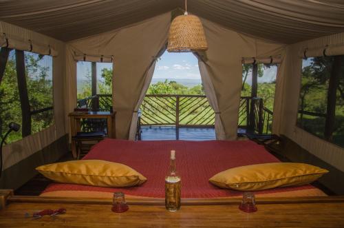 a bedroom with a bed in a tent with windows at Mara Siria Tented Camp & Cottages in Aitong