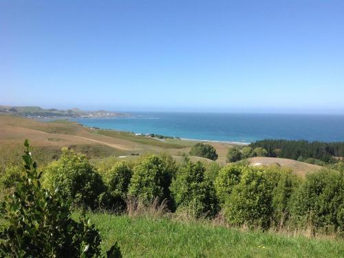 a view of the ocean from a hill with trees at The Fairways Accommodation Kaikoura in Kaikoura