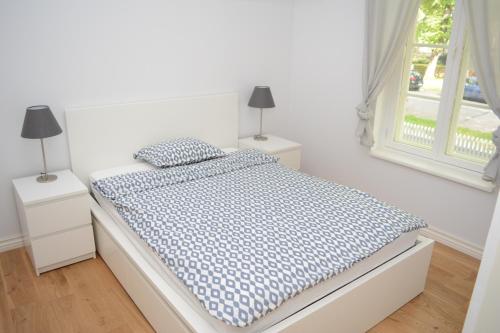 a white bedroom with a bed with a blue comforter at Koidula Villa in Pärnu