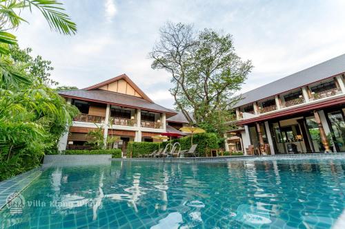a resort with a swimming pool in front of a building at Villa Klang Wiang in Chiang Mai