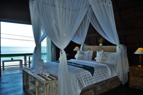 a bedroom with a canopy bed with a view of the ocean at Ocean Terrace Suite And Spa Luxury in Nusa Penida